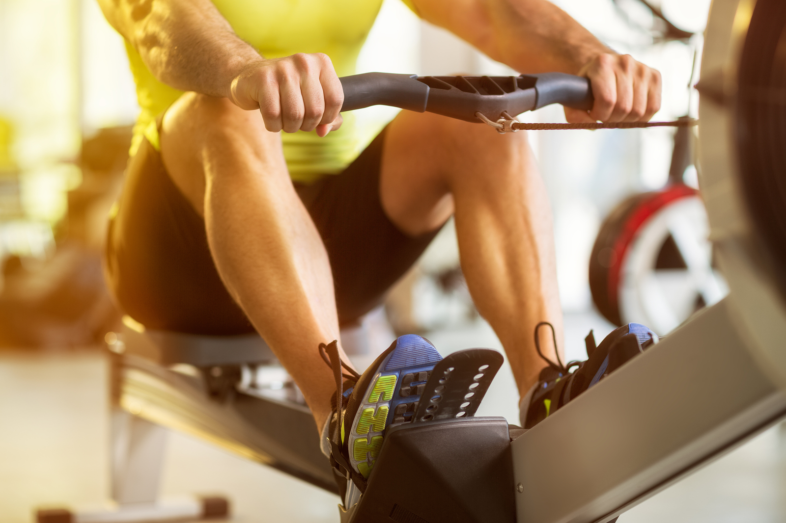 Fit man training on row machine in gym